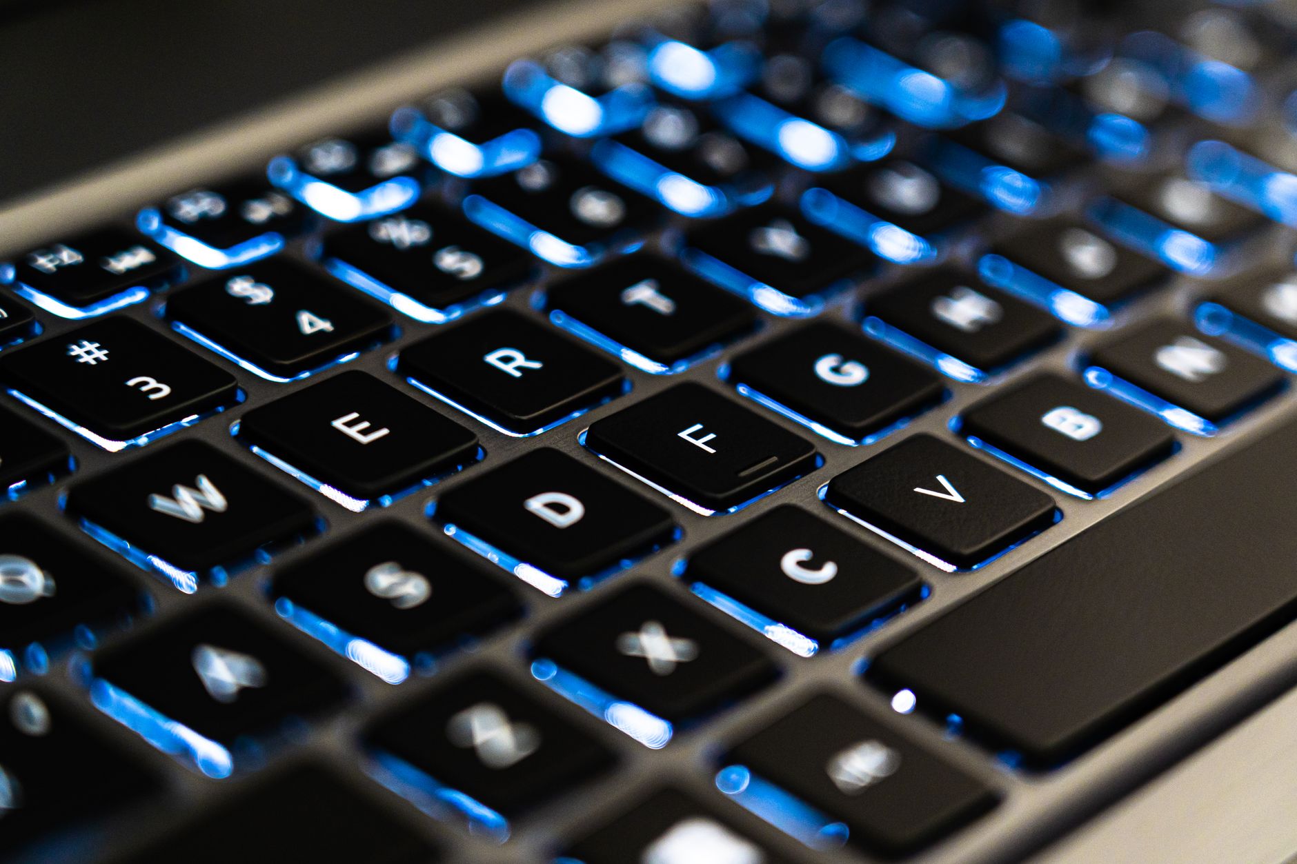 Detailopname van een verlicht laptoptoetsenbord met blauwe LED-verlichting.